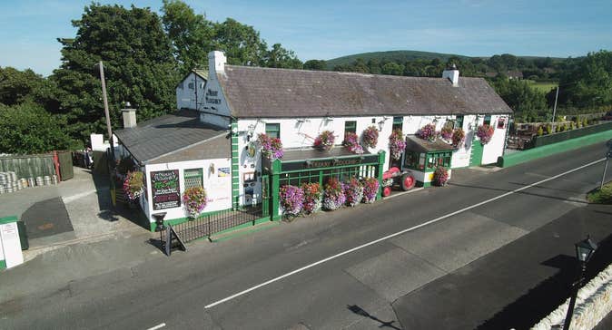 The exterior of the Merry Ploughboy Pub which is a white building with green trim and shopfront.