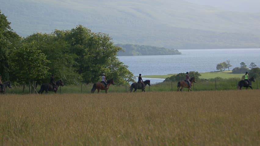 A group of people on horseback with a view of a lake and mountains in background