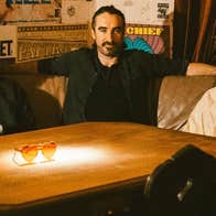 3 men seated around a wooden table on a corner couch