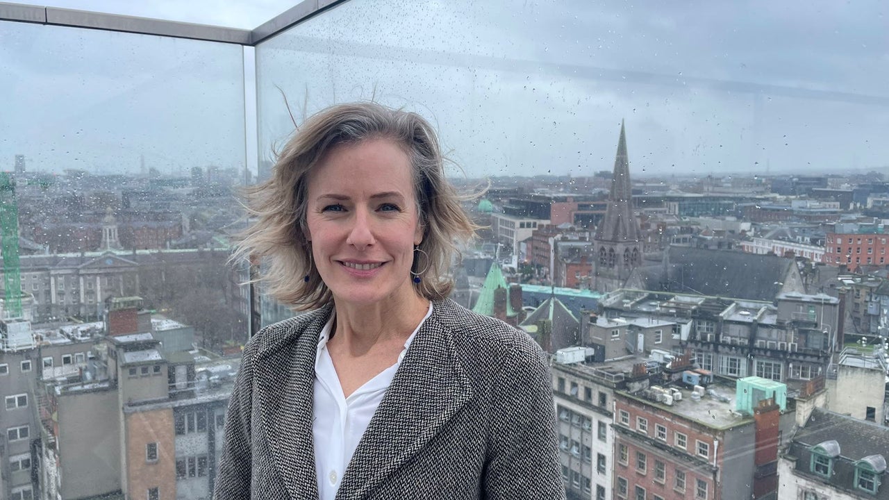 A lady standing on a balcony with a view out over Dublin as the back drop
