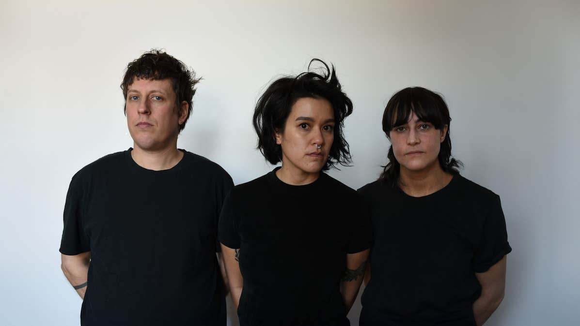 3 serious looking people all dressed in the same dark T-shirt, against plain grey background.