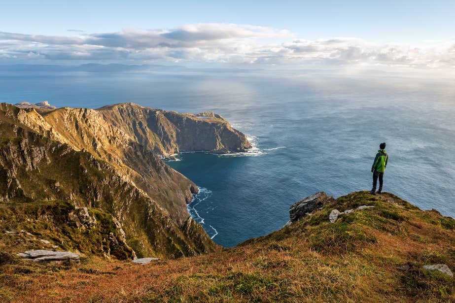 A person looking out at the sea from the edge of Sliabh Liag (Slieve League) in County Donegal.