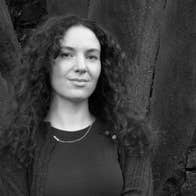 Síomha Callanan: Residency at Triskel Arts Centre, pictured standing in front of large tree trunks