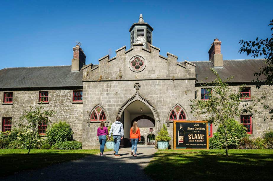 Three people walking through the entrance to Slane Distillery in Meath.
