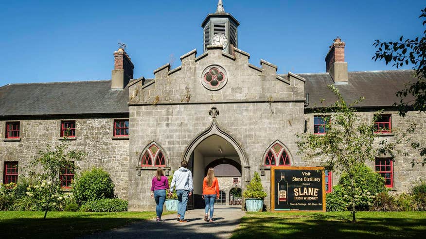 Three people walking through the entrance to Slane Distillery in Meath.