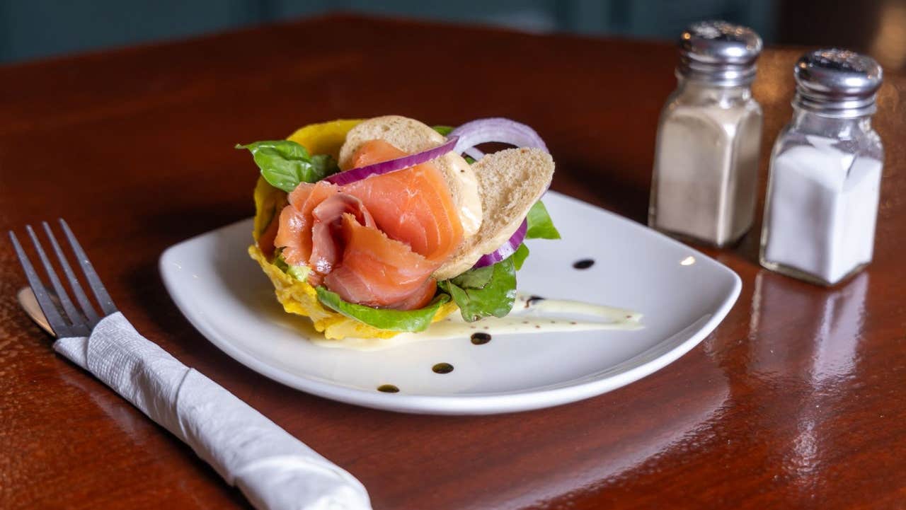 Smoked salmon served with bread and garnishes on a white plate with cutlery and condiments