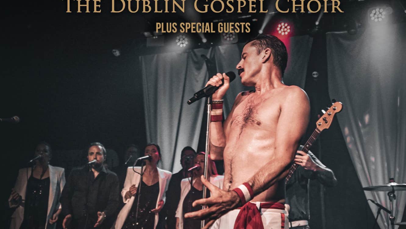 A bare chested man singing with a mic on a stage.
