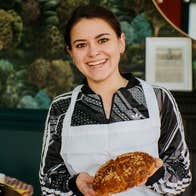 A lady in an apron holding an Irish soda bread scone