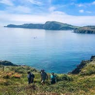 Three people on a walking trail with a view of the West Cork coastline in the background