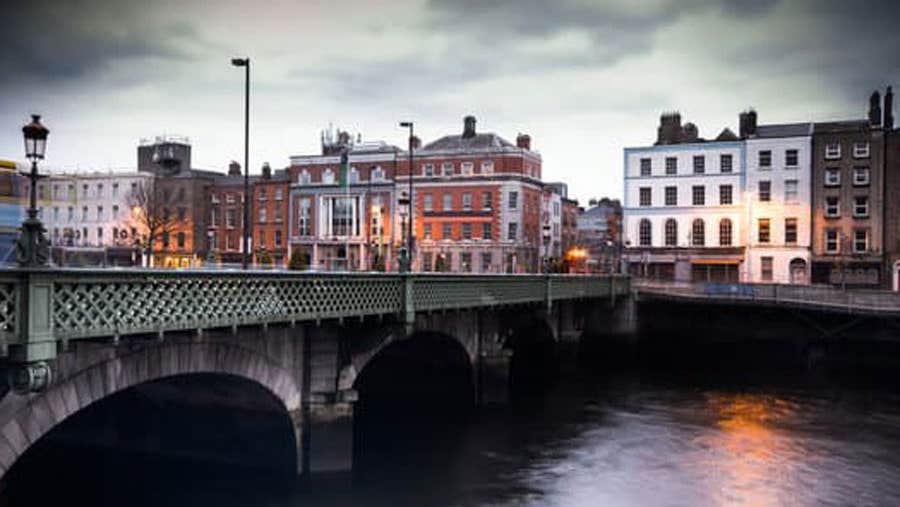 A evening view of a buildings overlooking a river beside a bridge