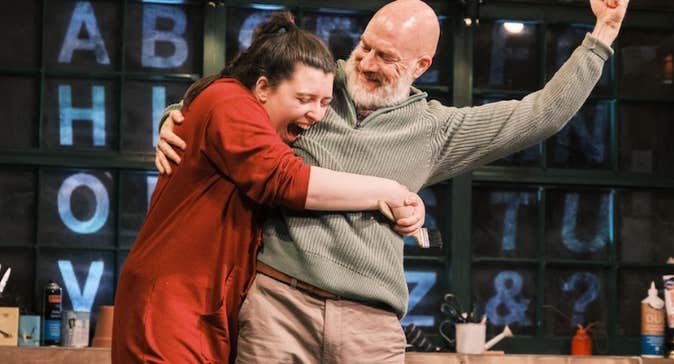 A joyful woman is hugging a smiling man who is holding a fist up in the air