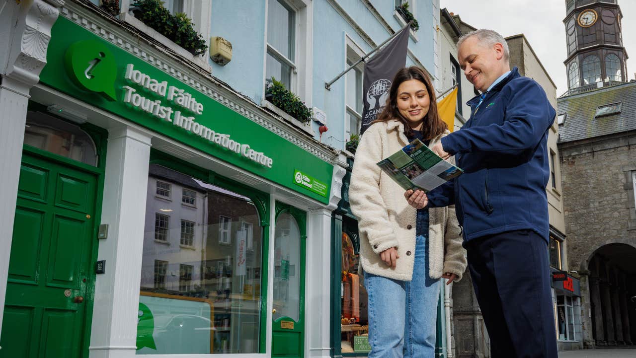 A member of staff at Kilkenny Tourist Information Centre assisting a visitor on the street outside on the street