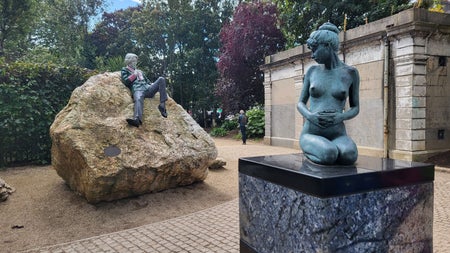 The playful reclining statue of Oscar Wilde perched on a boulder in Merrion Square, alongside one of the sculpture's companion figures — a popular photo stop on Dublin's literary trail.