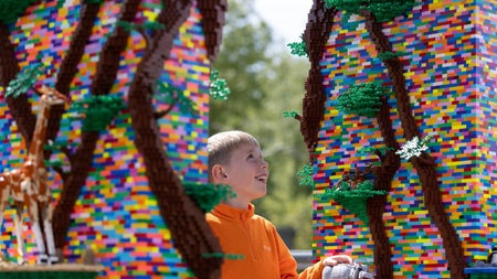Child exploring colourful Lego built structures and animals in an outdoor display at Dublin Zoo