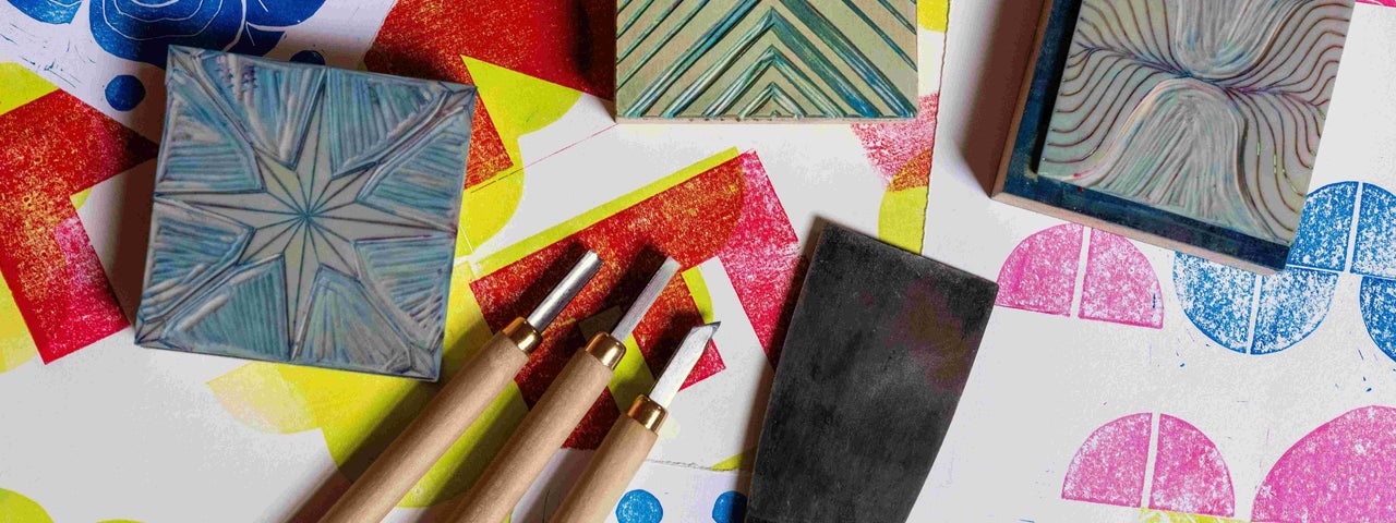 Print & Pattern with Susan Leen - Looking down at table containing print blocks, carving tools and paper with different coloured shapes on.