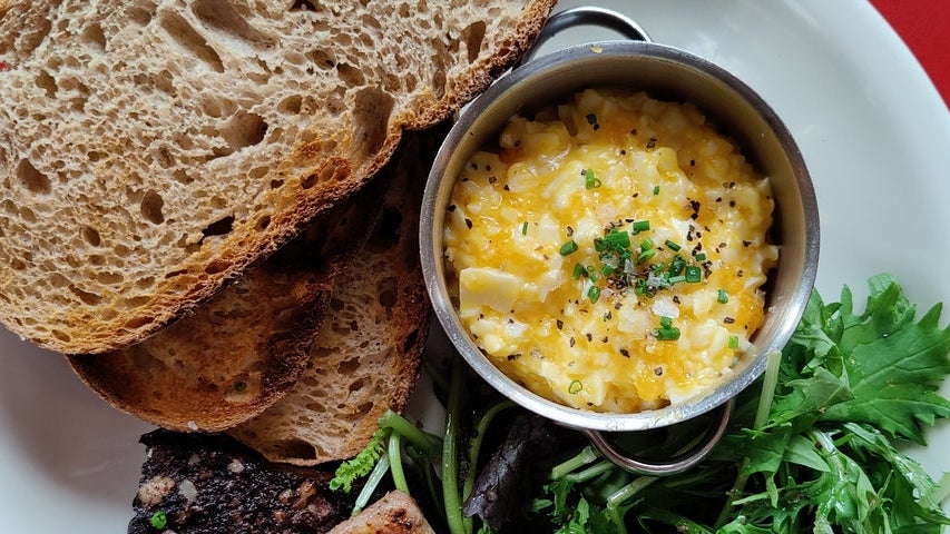 An egg dish with brown bread and green leaves on a plate