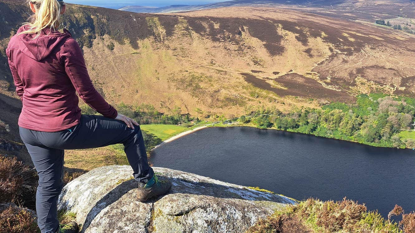 Person leaning on a rock looking down at a mountain valley
