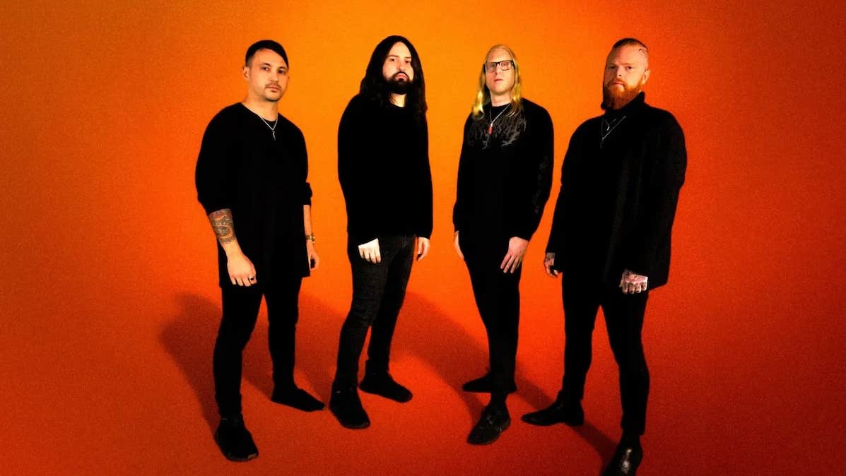 Illinois progressive metal band Born of Osiris, 4 serious looking men dressed all in black, against plain orange background.