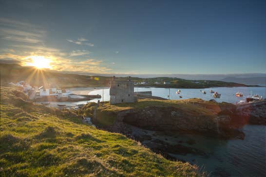 A view of the sun over Clare Island, Mayo with boats bobbing on the water in the background