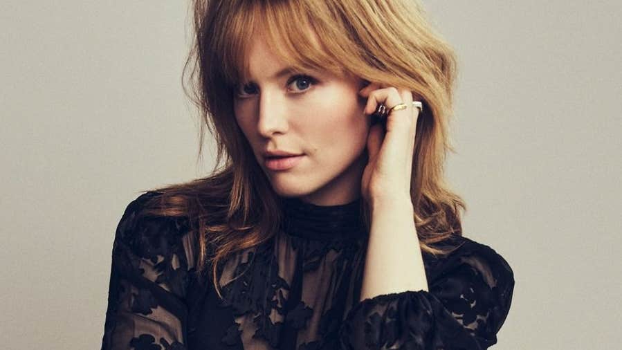 A woman touching her left ear, looking at the camera