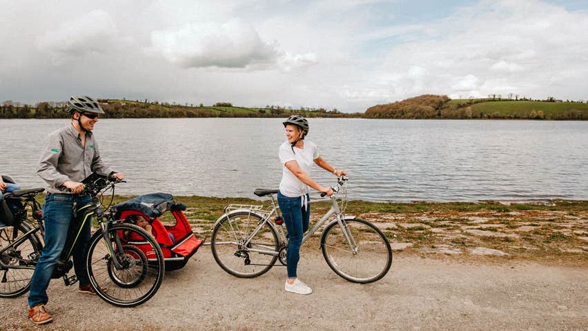 Couple with two children on bikes beside a lake