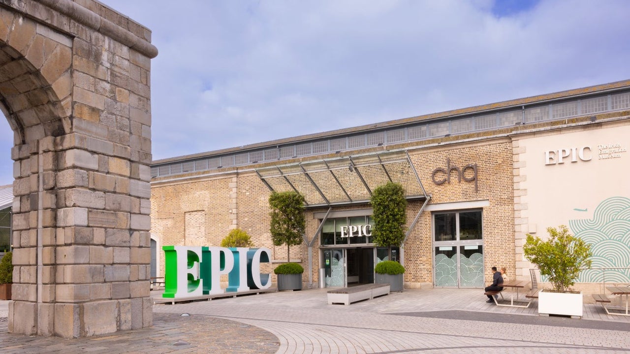 A courtyard entrance to a building with a large business logo outside