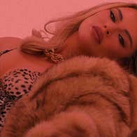 Pink tinted photo of person reclining back with a fur coat,