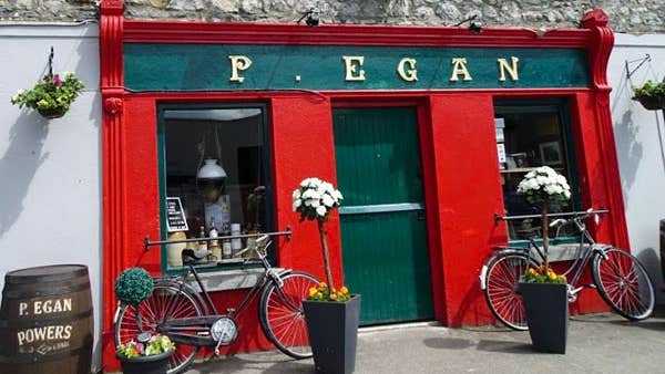 Exterior of P Egan Bar with red shopfront and bicycles and potted plants outside