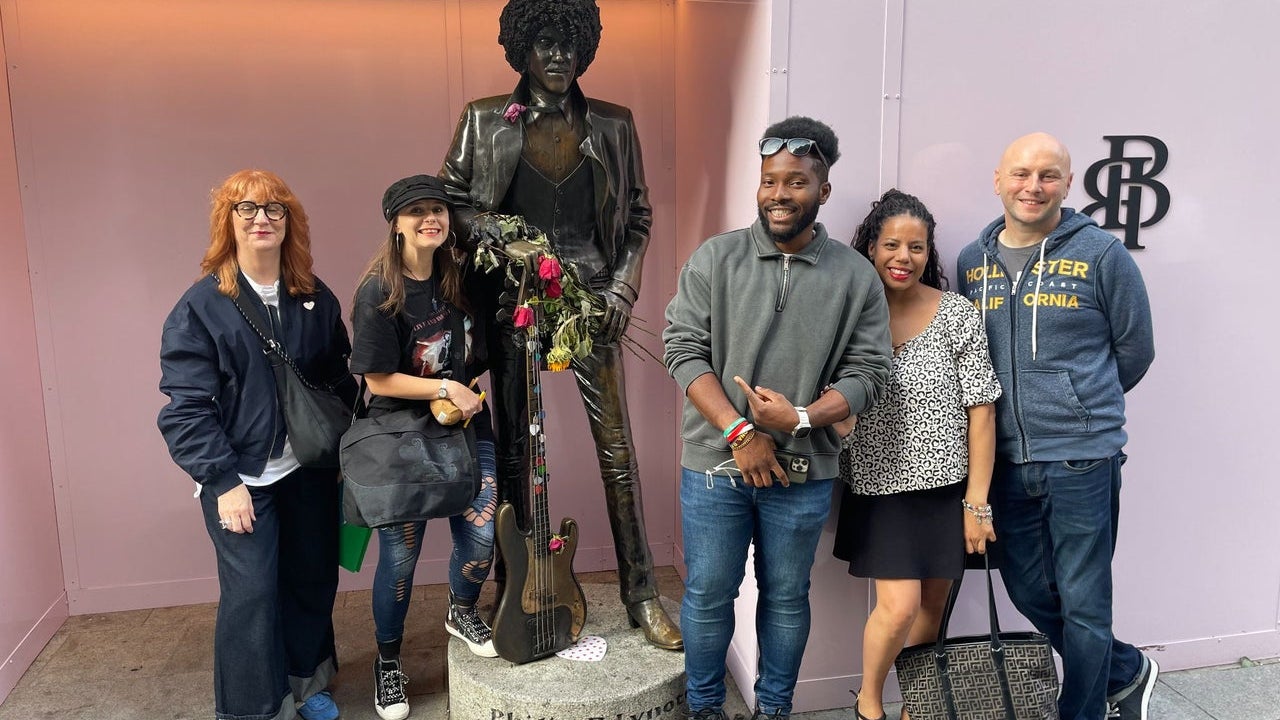 A walking group pose alongside a statue of the musician Phil Lynott