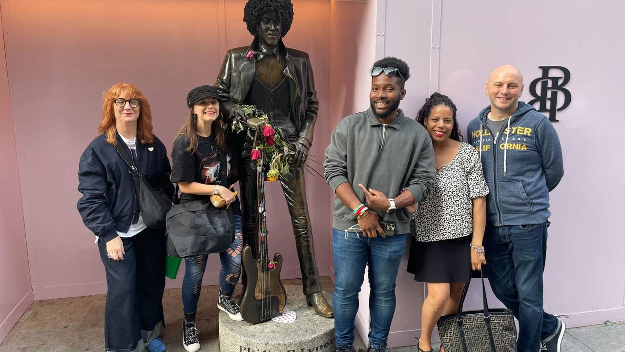 A walking group pose alongside a statue of the musician Phil Lynott