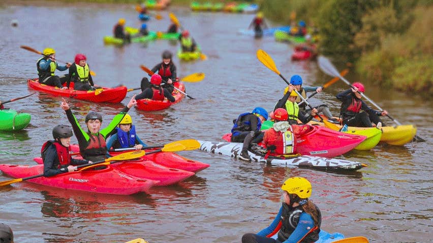 Several kids in kayaks on a river