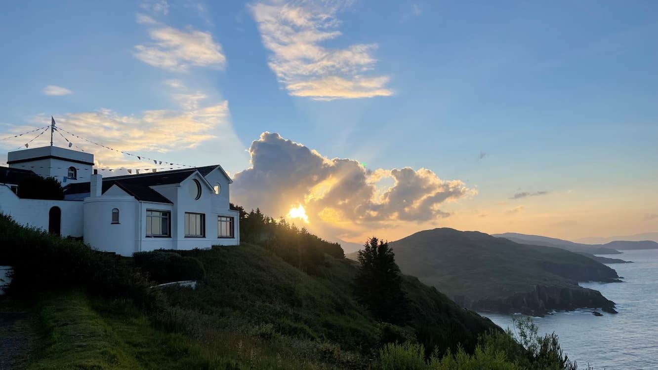 A white building on a hill near the sea.