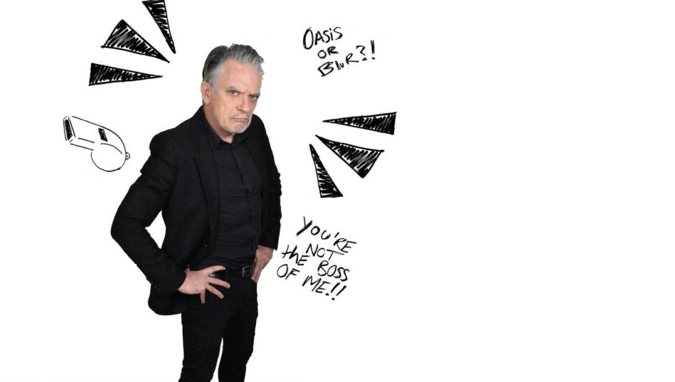 Image of comedian Joe Rooney dressed in black standing with his hands on his hips and a scowl on his face looking at the camera with cartoon type drawings and remarks around him against a white background.