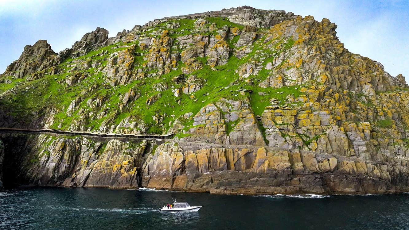 View of Skellig Michael from the sea with a tour boat sailing past