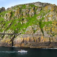 View of Skellig Michael from the sea with a tour boat sailing past