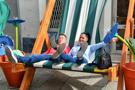 Smiling couple in Waterford City sharing a giant-sized beach chair.