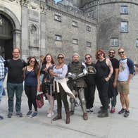 Tour group posing outside a castle with their tour guide dressed as a knight