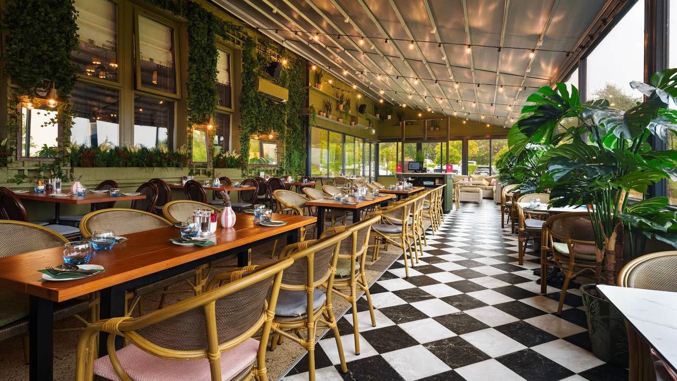 Three rows of tables set for service with chairs and a black and white tiled floor