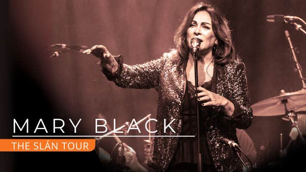 Mary Black The Slán Tour, a woman singing into a mic on a stand with right arm outstretched forward.