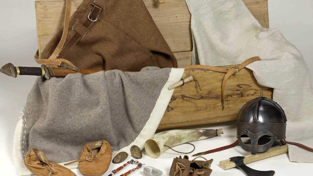 A replica Viking Chest with handmade clothes, booties and helmut with items of jewellery and axes.
