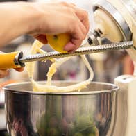 Christmas Cakes & Sweet Treats. A pair of hands grating a lemon into a large mixer bowl.