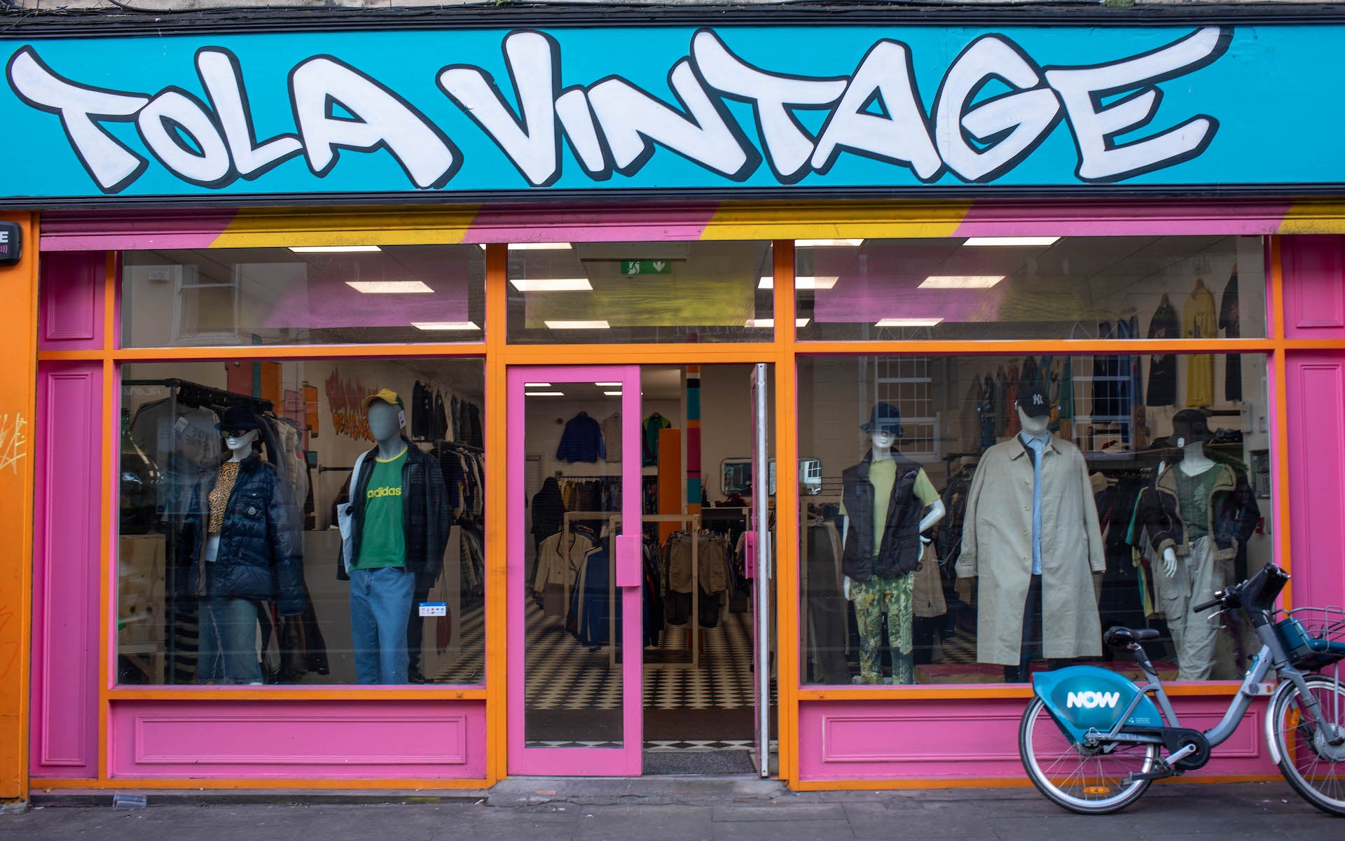 Colourful store front of Tola Vintage in Dublin. The store is painted in pink, orange and blue with the name painted in bold font.