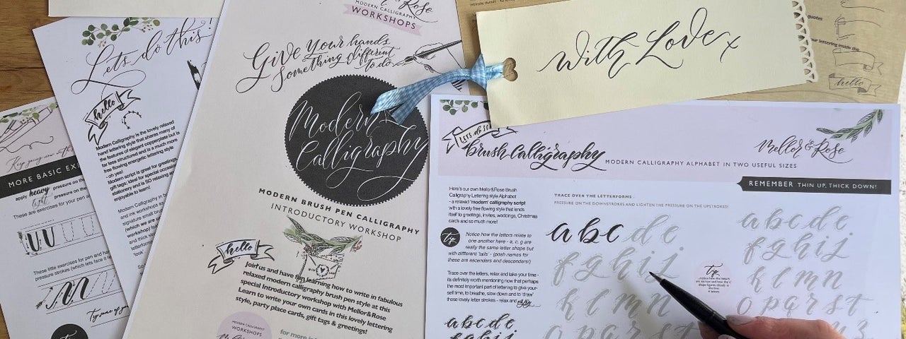 The Joy of Calligraphy - various sheets of paper containing text and letters with a hand holding a pen.