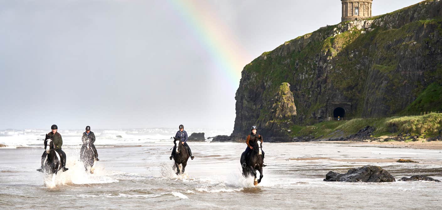 Group riding horses on Downhill Beach in Cork.