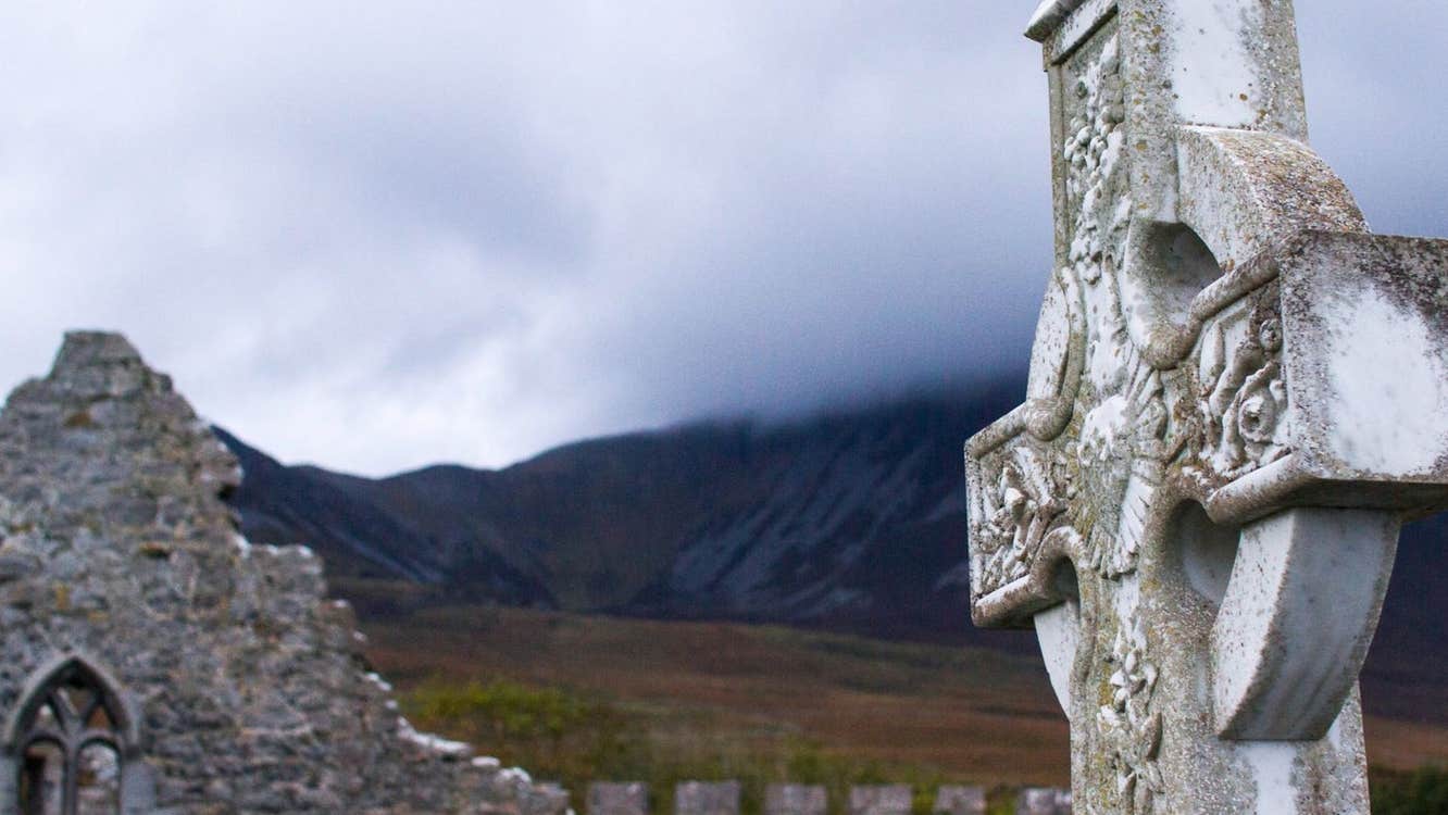 Close up image of a celtic cross and a church ruin