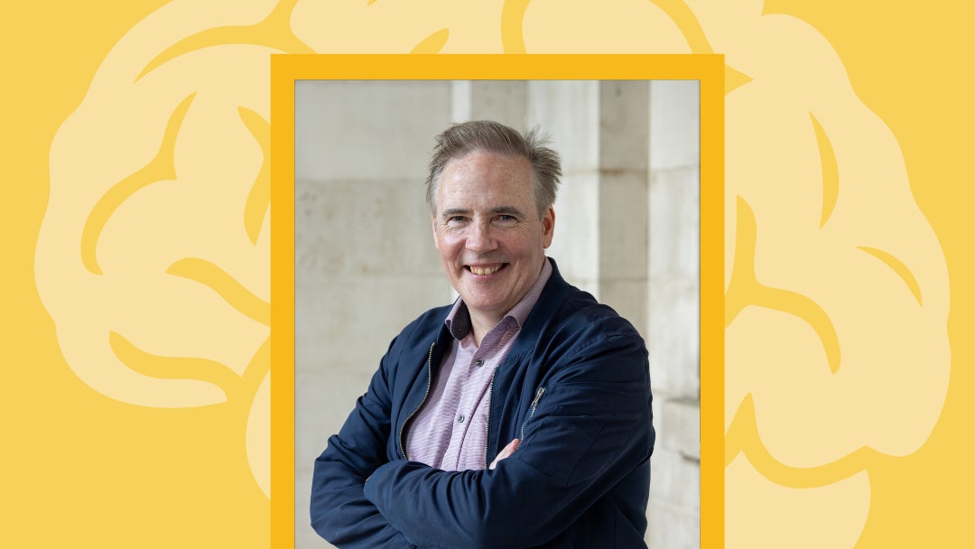 Poster in yellow with image of smiling man with arms crossed.