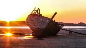 image of boat wreckage with sunset.