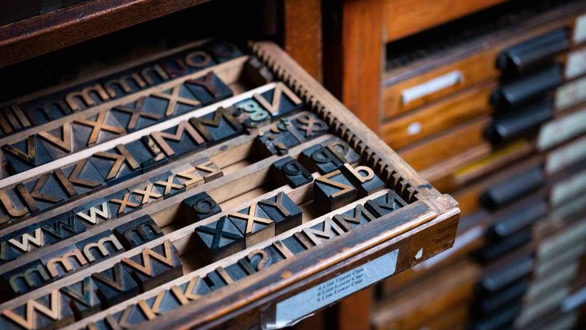 A case of wooden type partially pulled out of a type cabinet.
