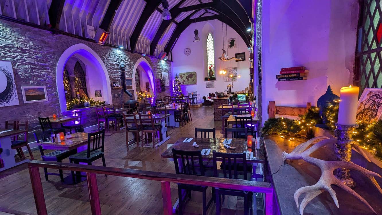 Interior of a converted church now a restaurant and lit by a purple hue