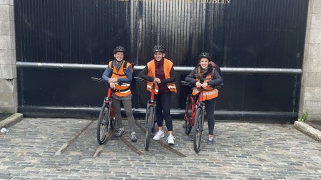 Three people on bikes outside Guinness storehouse gates